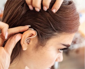 Woman adjusts hearing aid 